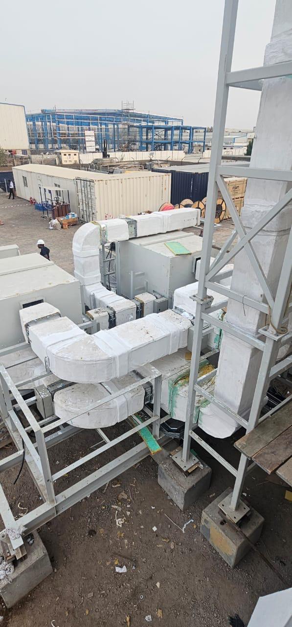 Insulated air distribution ductwork routed across a steel support platform on an industrial site in Dubai