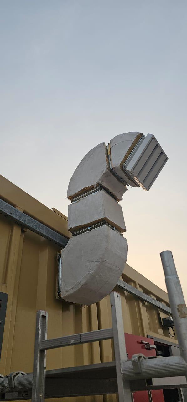 External pre-insulated duct elbow terminating at a weather louvre on a building facade