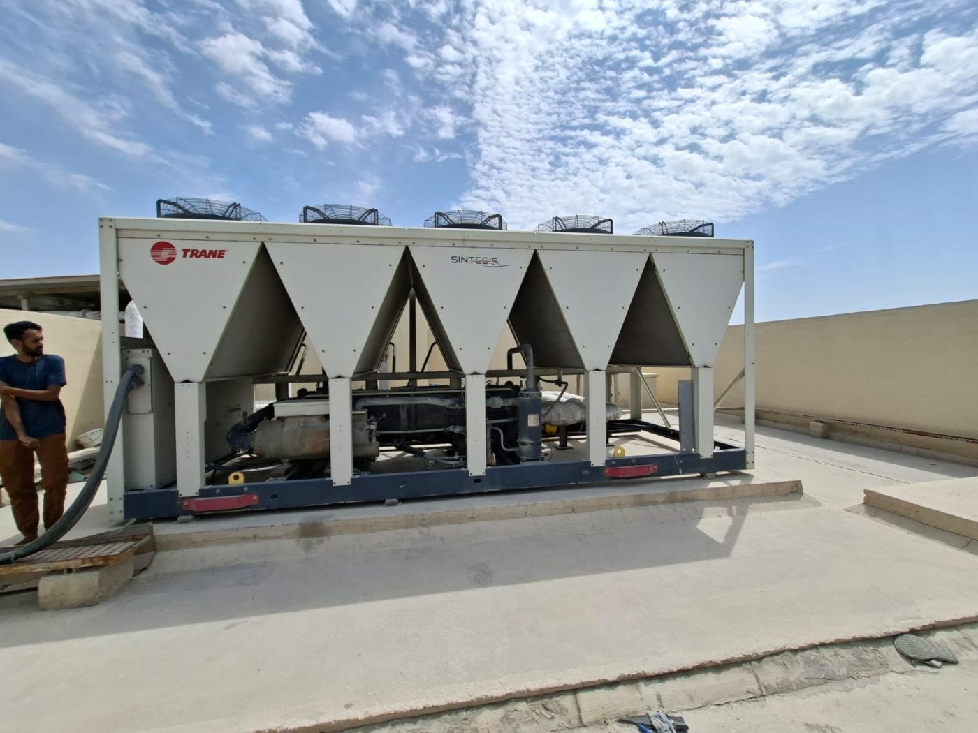 Air-cooled chiller on a Dubai rooftop with a Marjan Aldhyd technician alongside it