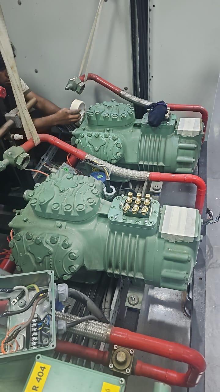 Semi-hermetic chiller compressors with refrigerant piping being serviced in a plant room